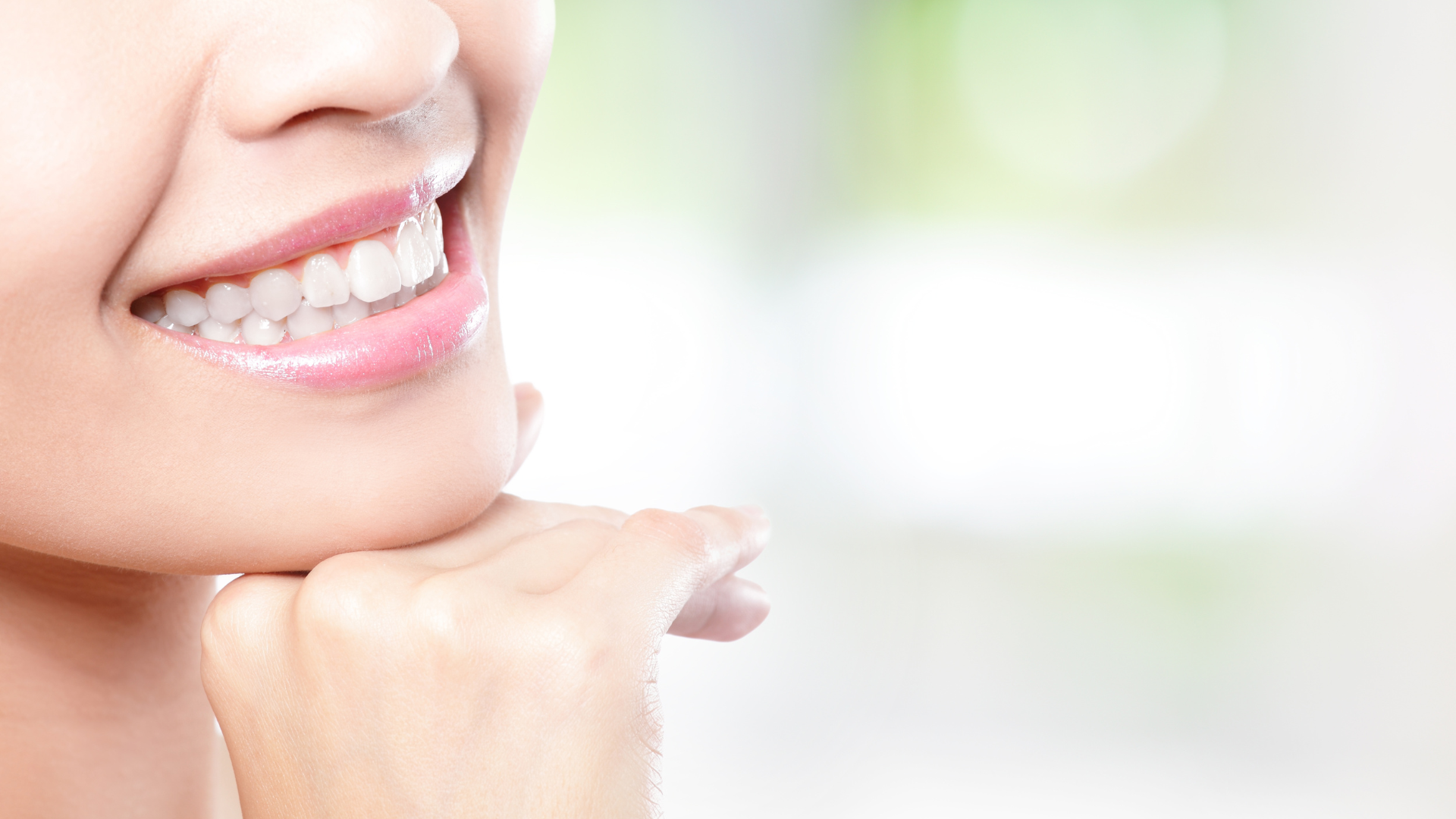 A close up of a woman 's smile with her hand on her chin.