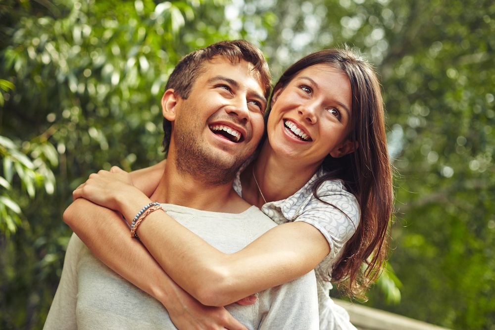 Smiling Couple Hugging Each Other Outdoors | Cosmetic Dentistry in Tustin, CA