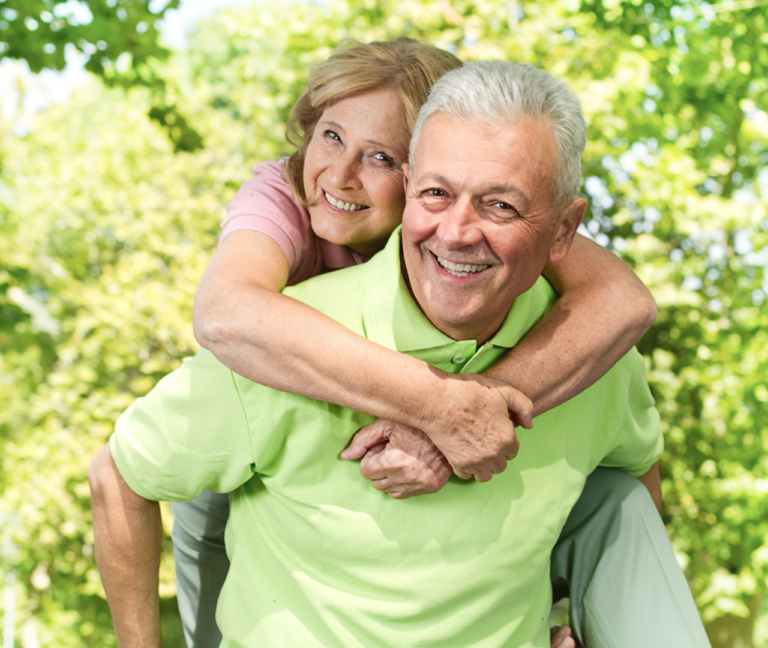 Elderly Couple Enjoying Piggyback Ride with Bright Smiles | Cosmetic Dentistry in Tustin, CA